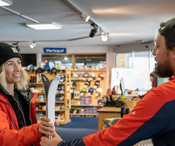 Eine Frau leiht einen Ski im Snow Fun Center in Hochoetz bei einem Mitarbeiter aus